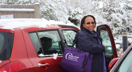Nurse with a Rennie Grove bag getting in to a snowy car to visit a patient at home