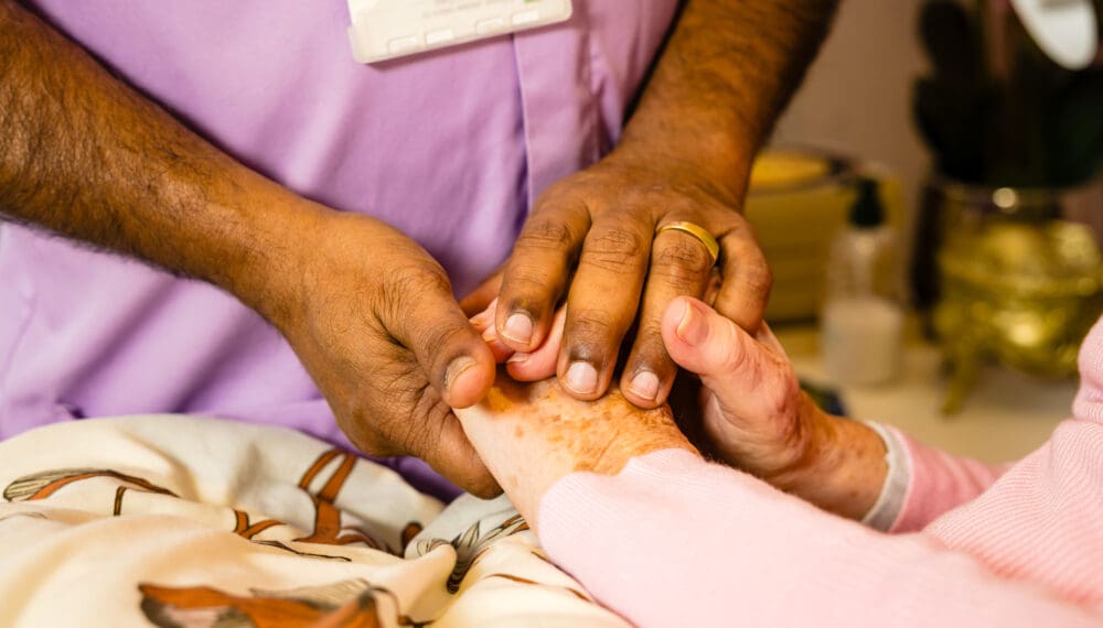 Rennie Grove Peace nurse holding someone's hand in comfort