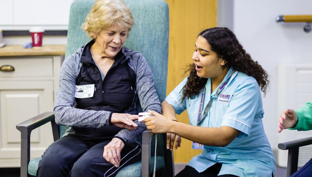 one women sitting and a nurse knelt down next to her