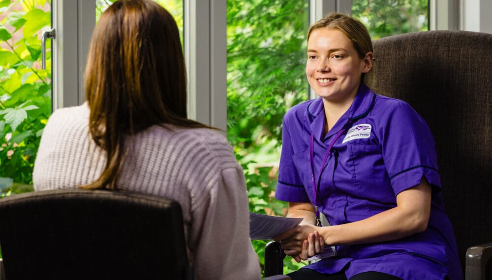 nurse speaking to a patient privately. nurse is smiling