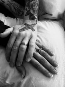 Two people holding hands with wedding rings