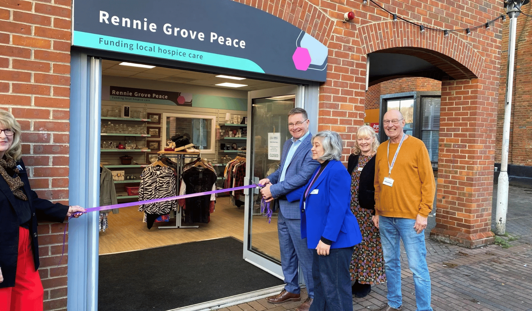 Ribbon cutting at the new Rennie Grove Peace shop in Chesham with staff and volunteers outside the entrance.