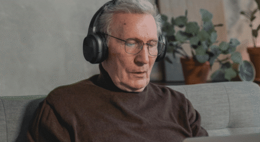man wearing headphones while joining an online webinar from home using a laptop