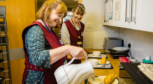 two volunteers preparing a meal for patients